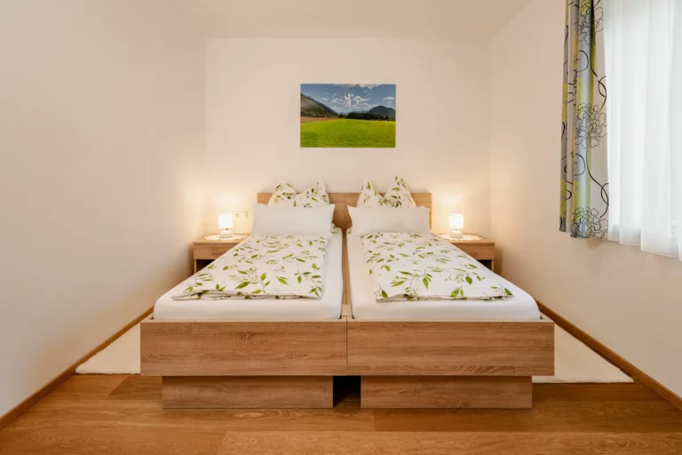 Unterkunft im Drautal. Übernachten im Rasdorferhof in Kärnten. Modernes Doppelzimmer "Grüne Wiese" mit Holzbetten, Bettwäsche und Blick ins Grüne.