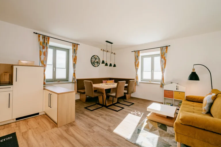 Helles modernes Wohn und Esszimmer im Rasdorferhof im Drautal mit Holzfußboden, gelbem Sofa, Möbeln und viel Tageslicht.